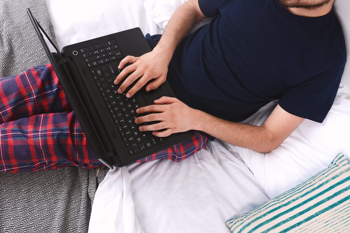 Nuori mies vertailee 50 000 euron lainatarjouksia kannettavalla tietokoneella rennosti kotona