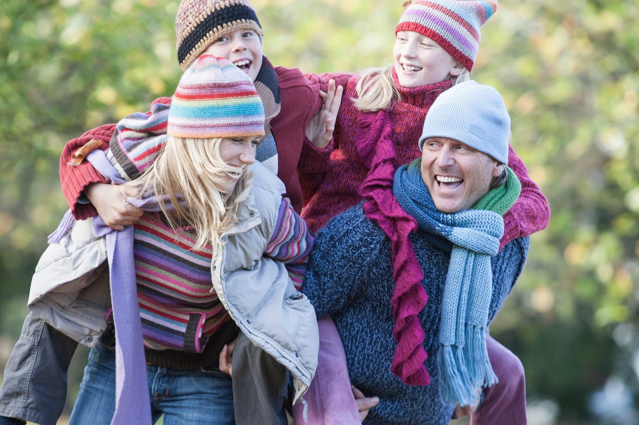 Onnellinen perhe puistossa viettämässä aikaa yhdessä, symboloiden taloudellista mielenrauhaa ja onnistunutta lainapäätöstä