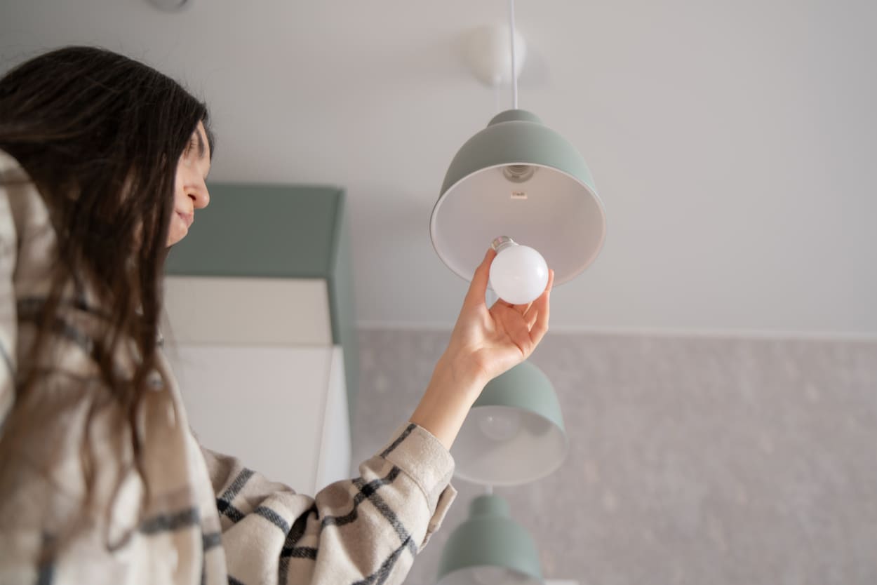 Nainen vaihtaa lamppua - pitkä 36 kk sähkösopimus on huoleton valinta