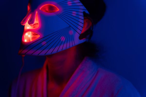 Nainen käyttämässä led-valonaamiota kotona