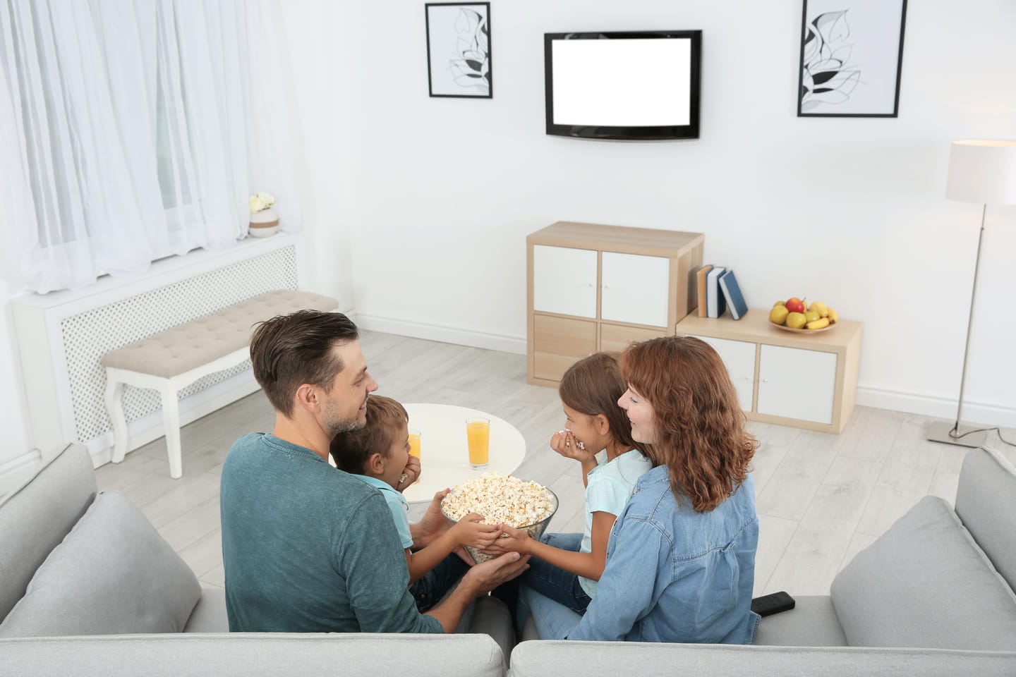 Perhe olohuoneessa television äärellä – edullinen sähkösopimus Kemi helpottaa arkea