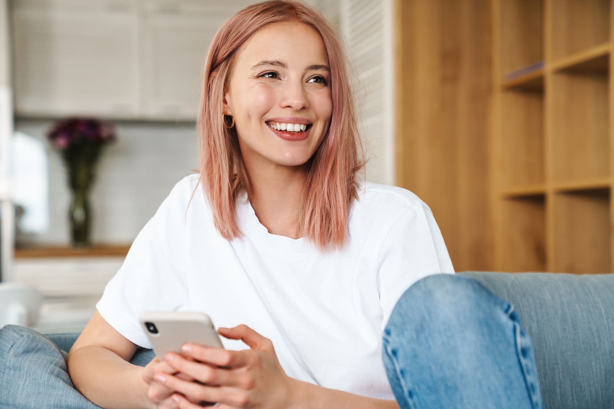 Nainen käyttää puhelinta lainanhakuun kotona