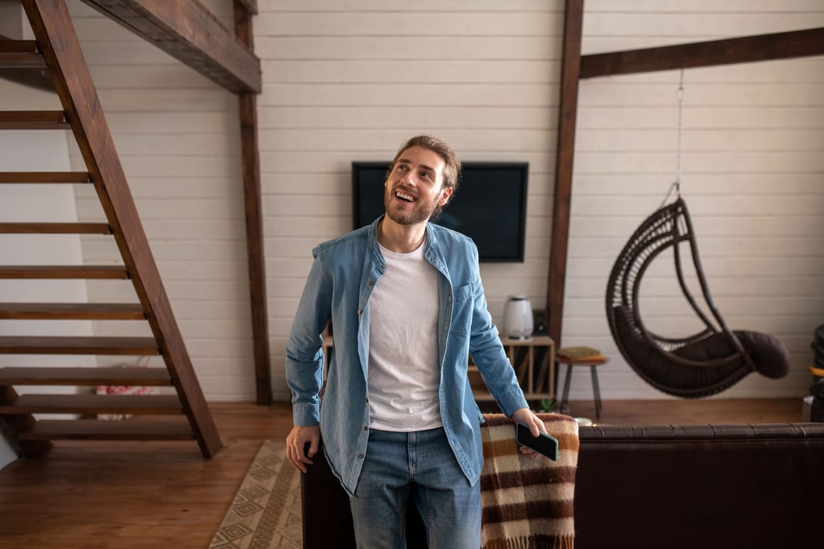 Iloinen mies etsii puhelimella markkinoiden halvinta lainaa