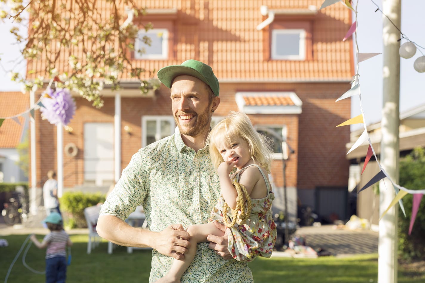 Isä kantaa lastaan pihalla ja miettii kuka voi saada lainaa perheellisenä unelmien toteuttamiseen