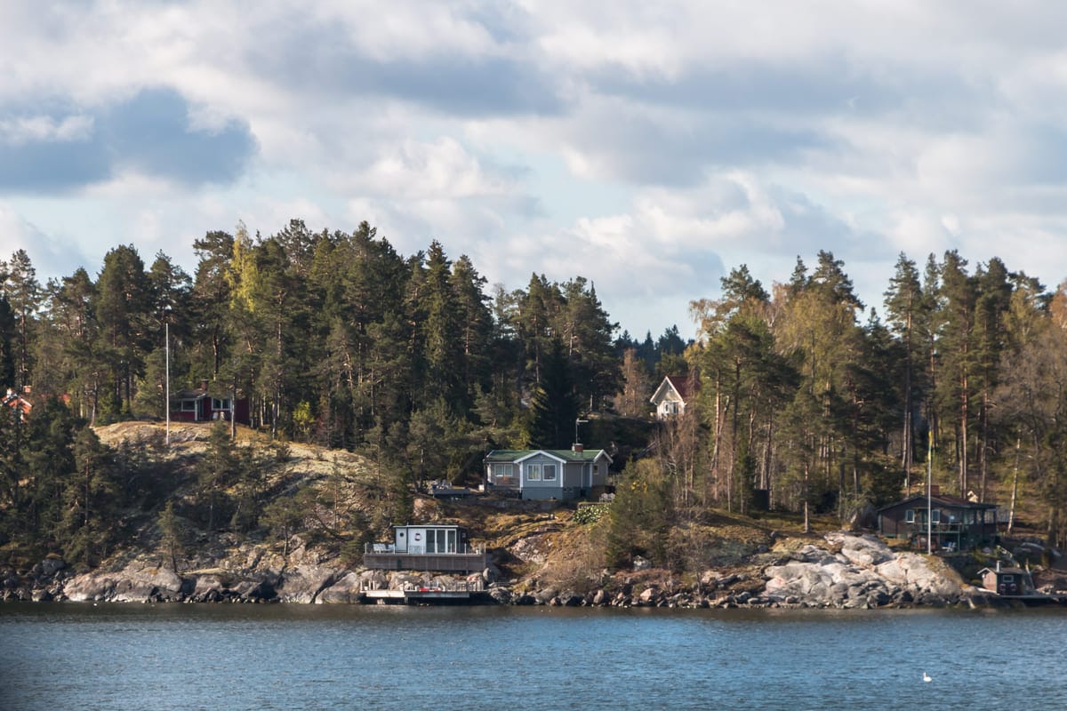 Kaunis saaristomaisema jossa punaisia mökkejä kallioisella rannalla