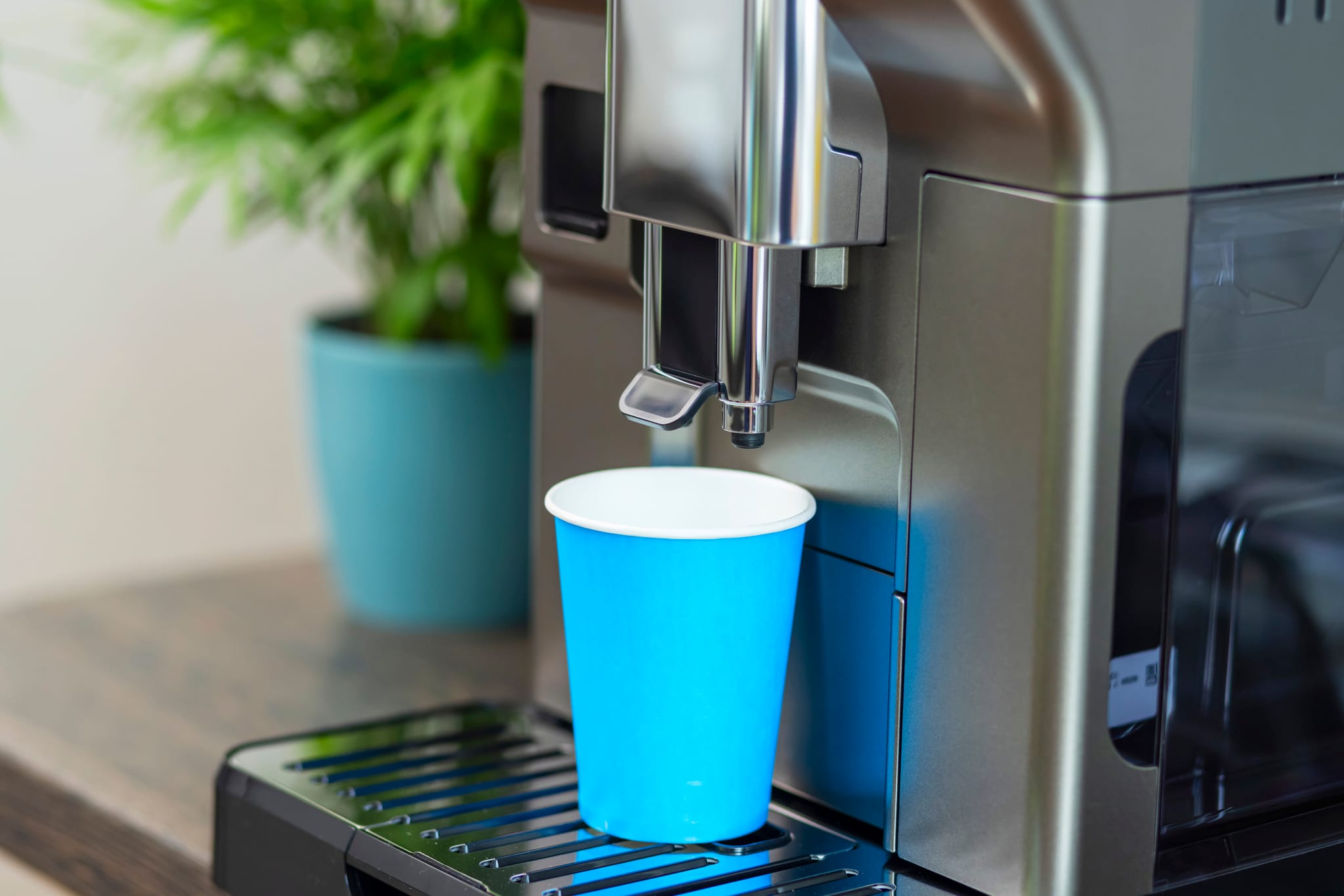 Dolce Gusto maitokahvikapselit vertailu: Löydä suosikkisi 14 Kuva: Moderni Dolce Gusto kahvikone valmistamassa maitokahvia siniseen kuppiin.